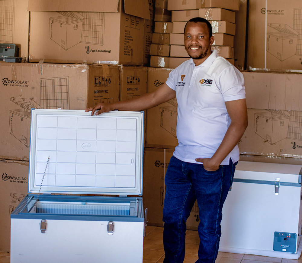 A man stands in a warehouse filled with solar appliances.